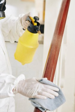 Temizlik görevlisinin merdiven korkuluklarına sıvı solüsyon sıkarak koronavirüsü ve yüzeydeki çeşitli bakterileri yok ettiği yakın plan görüntüsü.