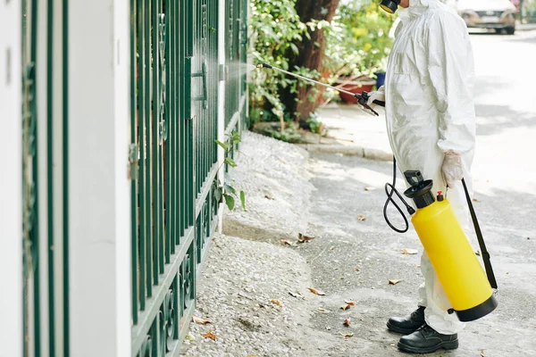Pracownik Masce Ochronnej Kombinezonie Dezynfekującym Ogrodzenie Sprayem Podczas Pandemii Covid — Zdjęcie stockowe