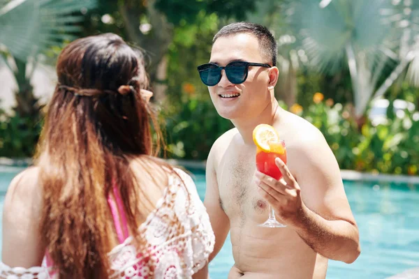 快乐的年轻亚洲男人和他的女朋友一起在游泳池游泳 喝着美味的水果鸡尾酒 — 图库照片