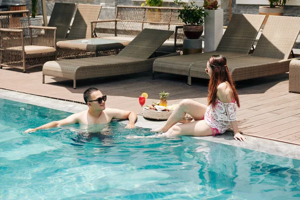 年轻夫妇在温泉胜地的游泳池里消磨时光 吃着美味的水果 — 图库照片