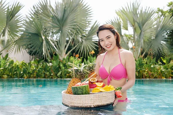 年轻美丽的越南女子站在游泳池里摆姿势摆满新鲜水果的画像 — 图库照片