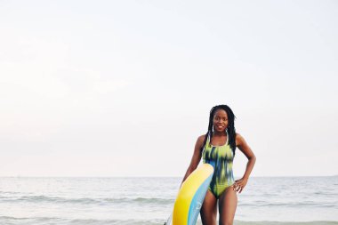 Okyanustan çıkarken elinde yiyecek taşıyan mutlu ve zinde bir genç kadının portresi.