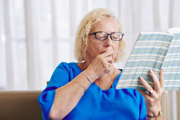 Aged Woman Glasses Sitting Sofa Living Room Reading Captivating Book — Stock Photo, Image