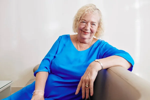 Portrait Positive Aged Woman Blue Dress Sitting Sofa Looking Camera — Stock Photo, Image