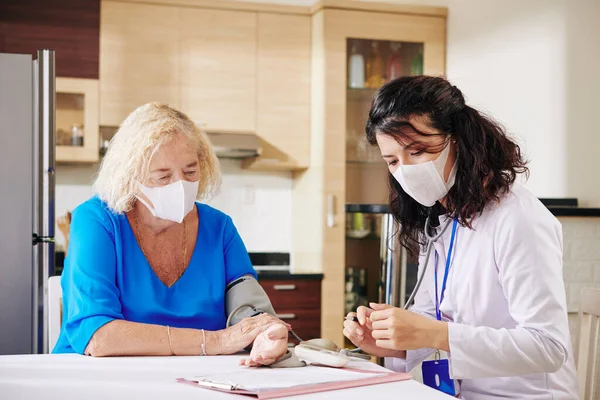 Tıbbi Maskeli Doktor Kadın Kıdemli Hastayı Ziyaret Ediyor Kan Basıncını — Stok fotoğraf