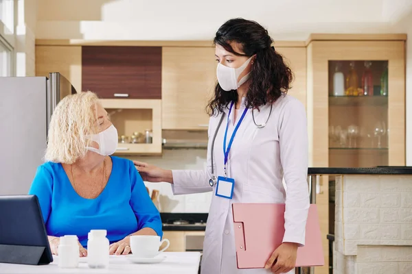 Kvinnlig Läkare Medicinsk Mask Klappa Äldre Kvinna Axeln När Besöker — Stockfoto