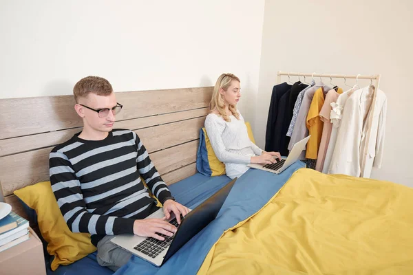 夫妇二人坐在床上的毛毯下 在隔离期间 在家中与他人保持距离时 在手提电脑上工作 — 图库照片
