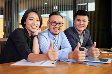 Masada birlikte oturan iki neşeli Asyalı erkek ve kadının yatay portresi.