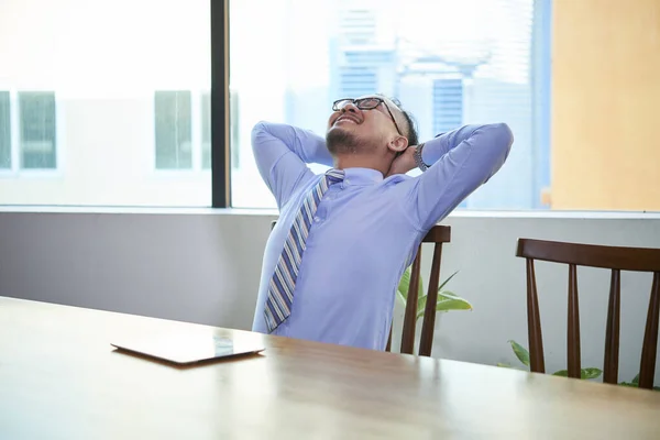 仕事が成功した後 オフィスのデスクで一人で座って青いシャツを着たアジア人男性 — ストック写真