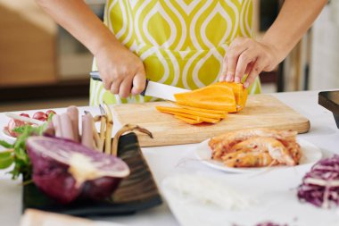 Önlüklü ev kadınının ince dilimlerle tatlı patatesleri keserken görüntüsü.