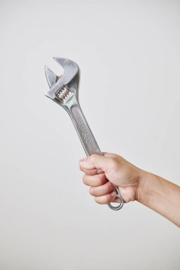 Açık gri renkte izole edilmiş, ayarlanabilir İngiliz anahtarı tutan inşaat işçisi ya da inşaat işçisi.