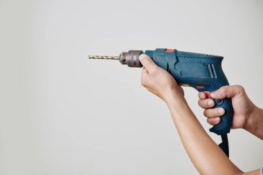 Duvarda delik açmak için elektrikli matkap tutan inşaatçının elleri