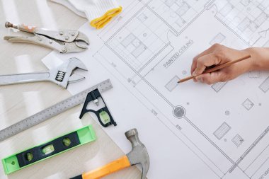 İnşaat mühendisi evin planlarını kontrol ediyor ve hangi parçaların yenilenmesi gerektiğine karar veriyor.