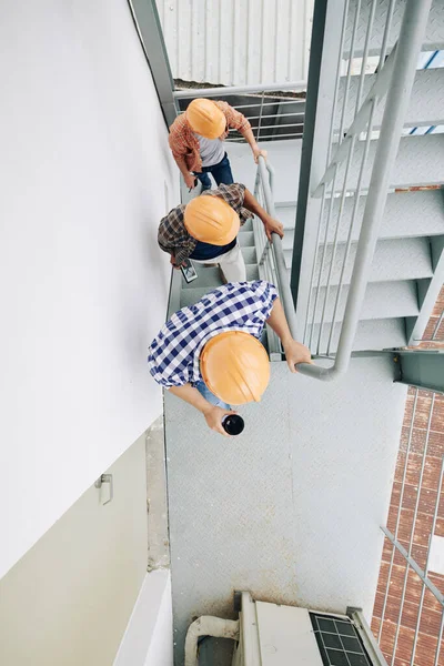 上から見た垂直2階に行くハードハットを身に着けている3人の認識できない建設専門家のショット コピースペース — ストック写真