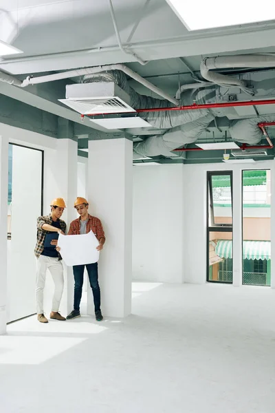 Dois Engenheiros Construção Modernos Juntos Sala Inacabada Olhando Para Papel — Fotografia de Stock