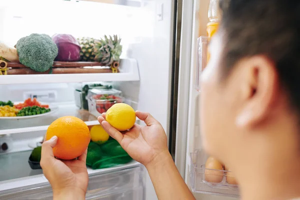 男人从打开的冰箱里取出新鲜的橙子和柠檬 — 图库照片