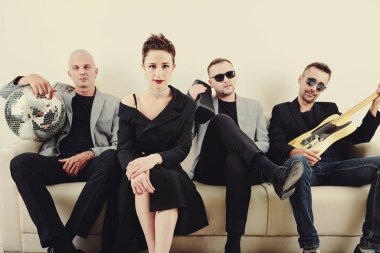 Gitarlı, hoparlörlü ve disko topu stüdyodaki kanepede oturan şık bir müzik grubu.