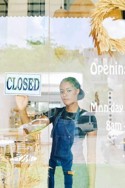 可悲的年轻黑人女面包店店主在玻璃门上贴上了封闭的标志 — 图库照片