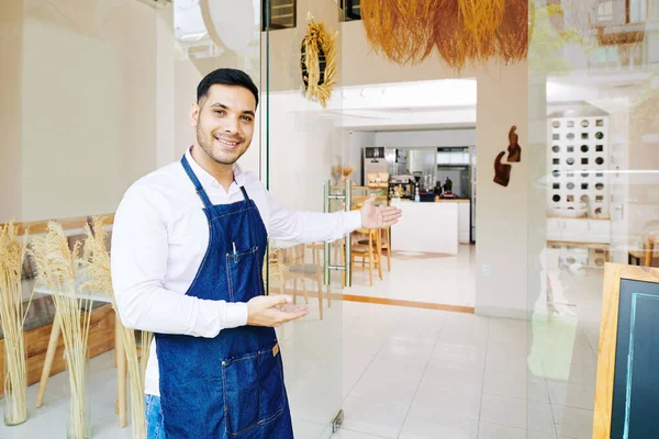 Красивий Усміхнений Власник Пекарні Фартусі Робить Вітальний Жест Запрошує Клієнтів — стокове фото