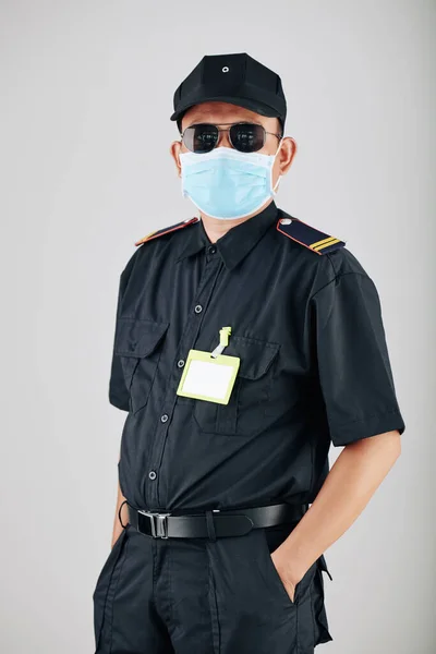 彼のシャツの上に空のバッジを持つサングラスや医療用マスクで自信を持って警察署ポケットに手を入れて カメラを見て — ストック写真