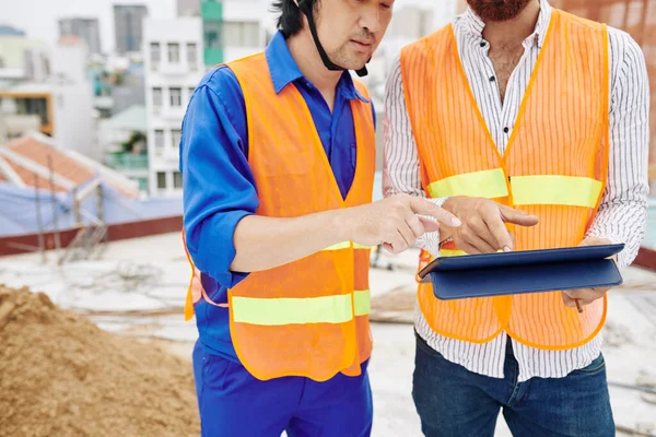 Immagine Ritagliata Dei Lavoratori Edili Giubbotti Arancione Brillante Discutendo Dettagli — Foto Stock