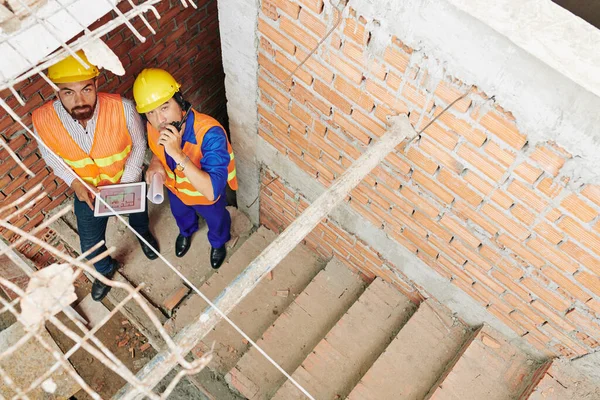 계단에서 워키토키를 사용하여 옥상에 노동자들과 의사소통을 안전모를 착용하고 사람들 — 스톡 사진