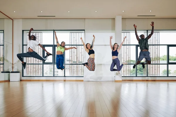 練習後の広々としたダンスホールで空中ジャンプする精力的な若者たち — ストック写真