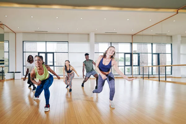 ダンススタジオでズンバクラスに参加して先生の後に動きを繰り返す幸せな若者たち — ストック写真