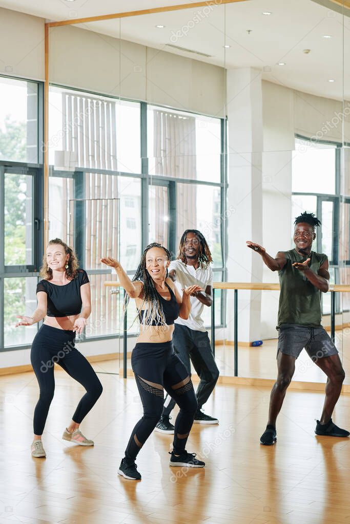 Excited happy group of young dancers training in studio in front of mirror