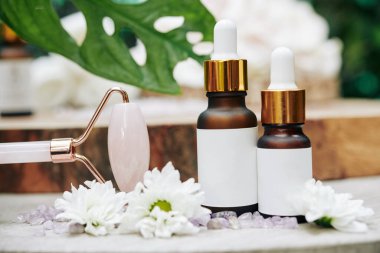 Gül kuvars masaj silindirleri ve yağlı şişeler ve spa prosedürlerini yenilemek için serumlar.