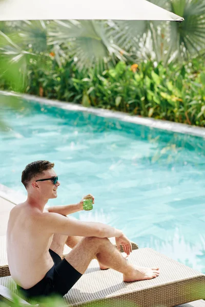 幸せな若いです男支出晴れた日によってプールと飲む冷たいカクテル — ストック写真
