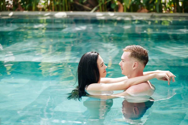 恋爱中的年轻夫妇站在游泳池里 互相拥抱 互相望着对方 — 图库照片