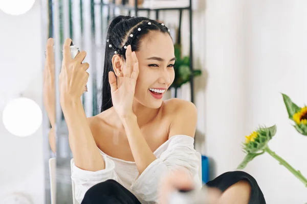 若いアジアの女性は 髪のスプレーを適用する際に目を細めて手で顔を覆う — ストック写真