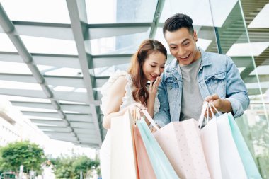 Heyecanlı genç Vietnamlı çift alışveriş torbalarının içine bakıyor.