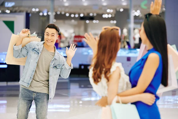 Sonriente Guapo Joven Asiático Saludando Con Mano Sus Amigas Centro —  Fotos de Stock