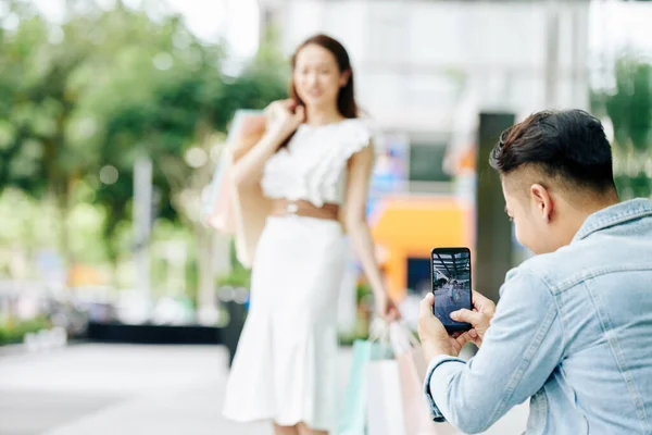 Ung Man Tar Foto Flickvän Poserar Utomhus Med Shoppingväskor — Stockfoto