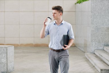 Deri evrak klasörüyle yakışıklı genç girişimci ve açık havada bir fincan kahve.