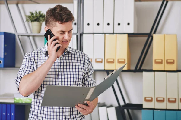 Młody Biznesmen Czyta Raport Otwartym Folderze Rozmawia Przez Telefon Kolegą — Zdjęcie stockowe