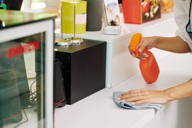 Küçük kafe sahibi tezgahın yüzeyine dezenfekte deterjanı püskürtüp yumuşak bez ile siliyor.