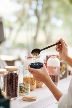 Garsonun elleri müşteriler için büyük bir kaşık dolusu dondurma ve dondurma koyuyor.