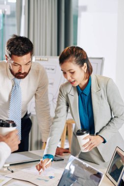 Finans raporunu işaret eden bir fincan kahve ile genç Vietnamlı kadın girişimci