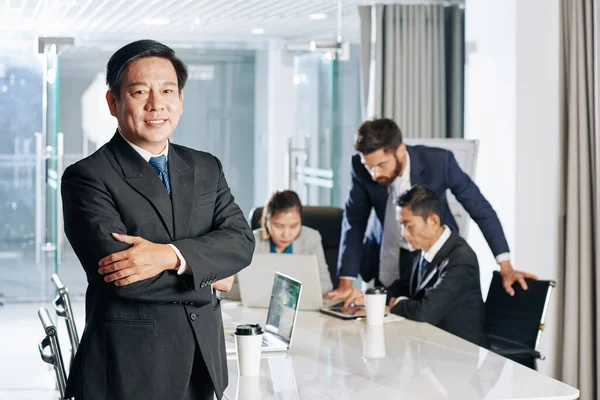 Positive Confident Mature Vietnamese Entrepreneur Standing Arms Folded Table Meeting — Stock Photo, Image