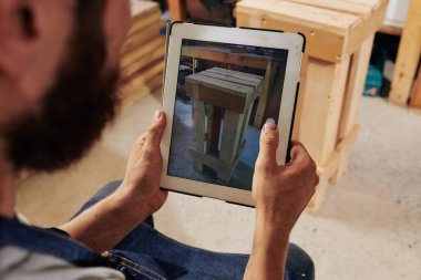 Marangoz dijital tabletle atölyedeki ahşap standı fotoğrafladı ve web sitesine yükledi.