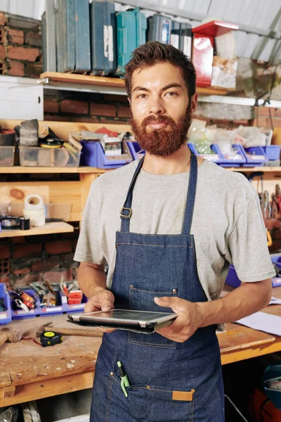 Portret Van Lachende Bebaarde Timmerman Spijkerschort Werkplaats Met Tabletcomputer Handen — Stockfoto