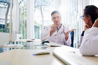 Ciddi genç pratisyen hekimler, genç bayan meslektaşlarıyla yeni hastalık tedavi yöntemlerini tartışıyor.