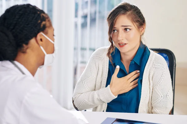 Pretty young woman complaining about chest pain when visiting doctor