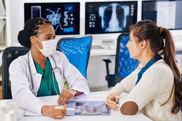 Schwarze Hausärztin Medizinischer Maske Diskutiert Röntgenbild Mit Ernsthafter Patientin Und — Stockfoto