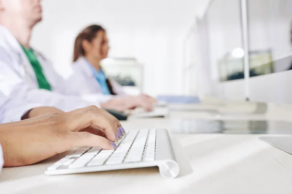 在医务室的计算机上工作并以在线形式输入病人数据的女医生的特写图像 — 图库照片