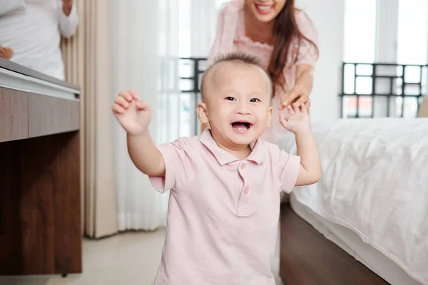 快乐的年轻亚洲女人松开了正在微笑着走向镜头的孩子的手 — 图库照片