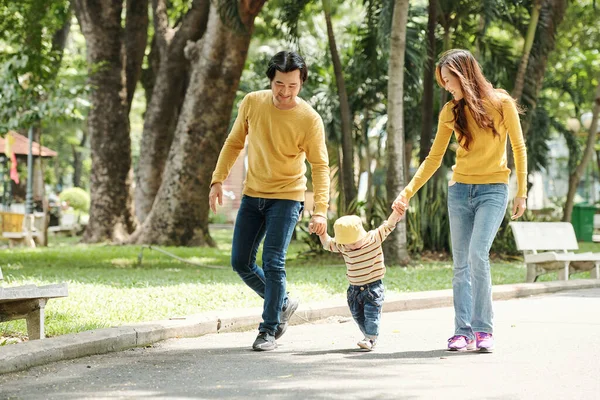在公园散步时 快乐的父亲和母亲牵着男婴的手 — 图库照片